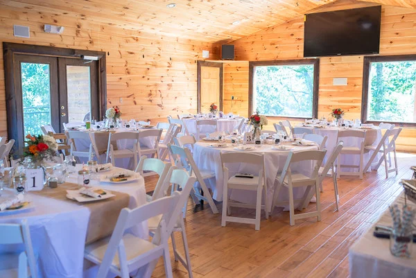 Rustic wedding reception hall with round tables and white chairs at Moose Hollow Lodge in Pigeon Forge