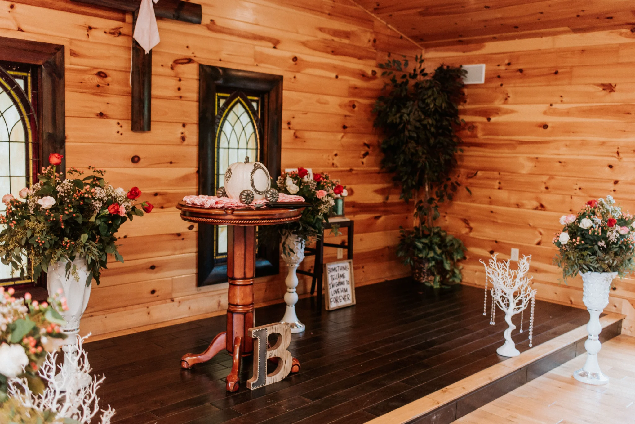 Wood-paneled wedding chapel altar with rose bouquets and stained glass at Moose Hollow Lodge in Pigeon Forge