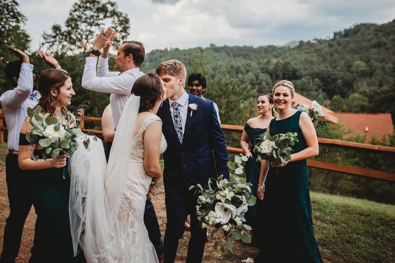 Wedding couple kissing with bridal party and Smoky Mountain views at Moose Hollow Lodge in Pigeon Forge near Dollywood.