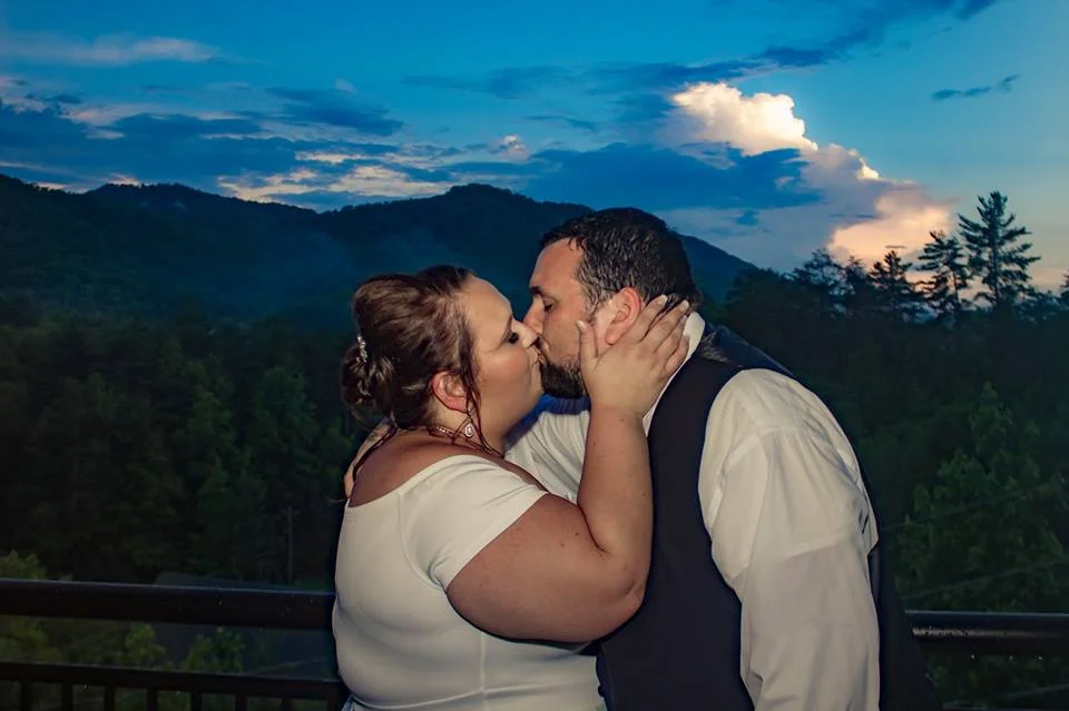 Newlyweds kissing on deck with Smoky Mountain views near Dollywood at Moose Hollow Lodge in Pigeon Forge