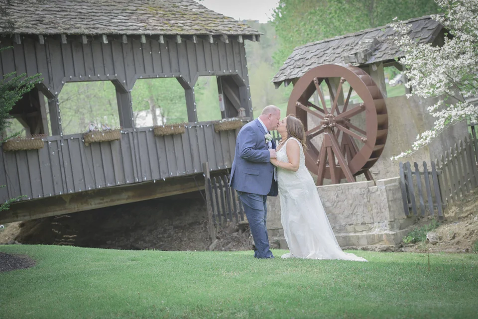 Wedding couple kissing by a covered bridge and water wheel at Moose Hollow Lodge in Pigeon Forge near Smoky Mountains