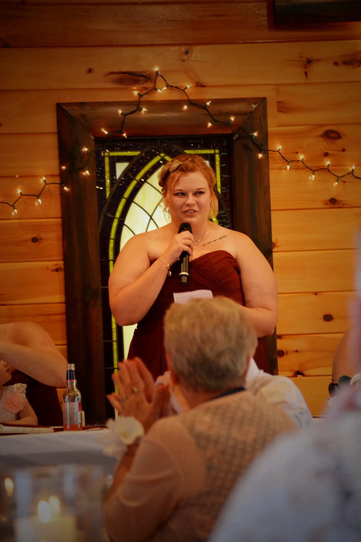 Wedding toast in a rustic reception hall with wood walls and string lights at Moose Hollow Lodge in Pigeon Forge.