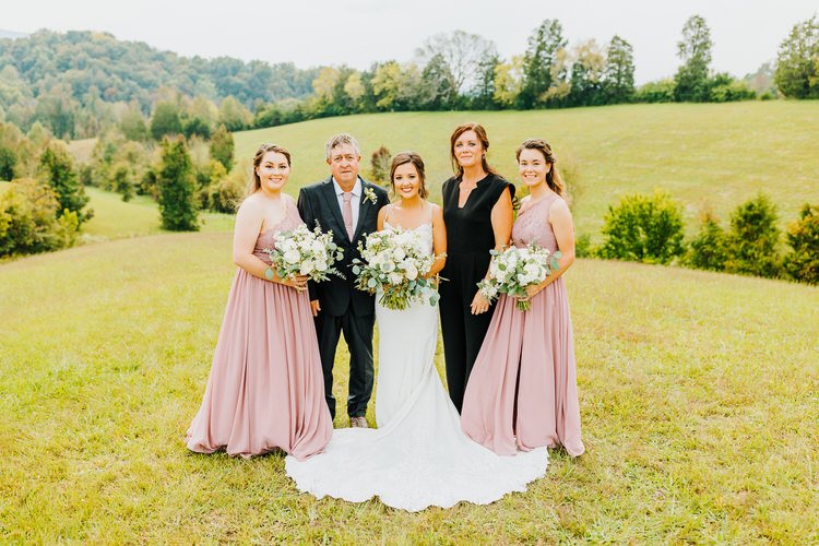 Bride and four family members pose in a grassy field with rolling hills and trees in the background at Moose Hollow Lodge.