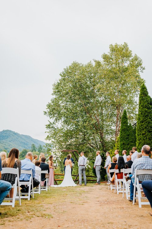 Outdoor wedding ceremony at Moose Hollow Lodge with guests seated, a couple at an arbor, and mountains in the distance.