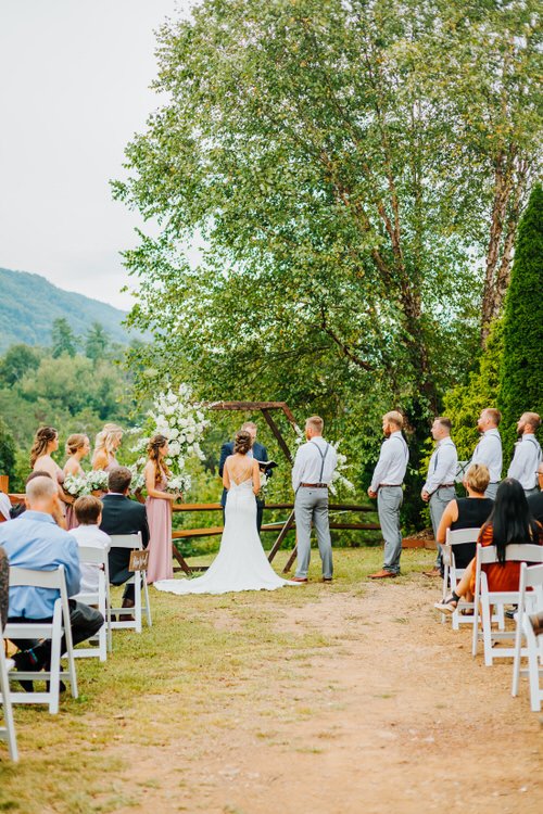 Outdoor wedding ceremony at Moose Hollow Lodge with bride, groom, wedding party, guests. Mountains and trees in background.