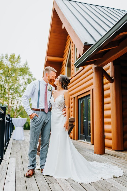 Couple in wedding attire on a wooden deck in front of a log cabin structure at Moose Hollow Lodge.