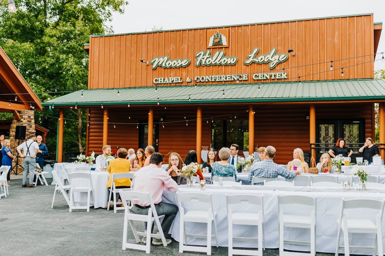 Guests seated at outdoor reception tables in front of Moose Hollow Lodge Chapel & Conference Center with string lights.