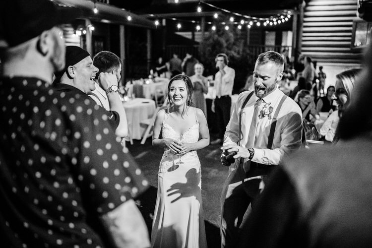 Bride and groom at a night wedding reception with guests at Moose Hollow Lodge. String lights overhead.