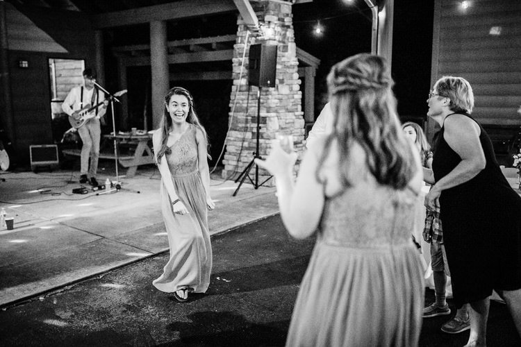 Wedding guests dance at an outdoor evening reception with live music and string lights at Moose Hollow Lodge venue.